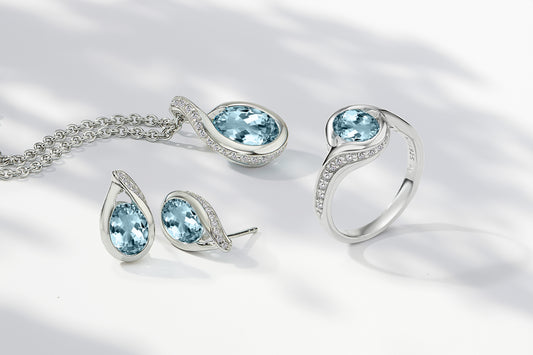 Ein romantisches Schmuckset aus Silber mit funkelnden Zirkonia und einem blauen Topas in tropfenförmigem Schliff. Das Set enthält Ohrstecker, einen Anhänger an einer langen Kette und einen passenden Ring. Zeitlos und elegant - perfekt für jeden Anlass.